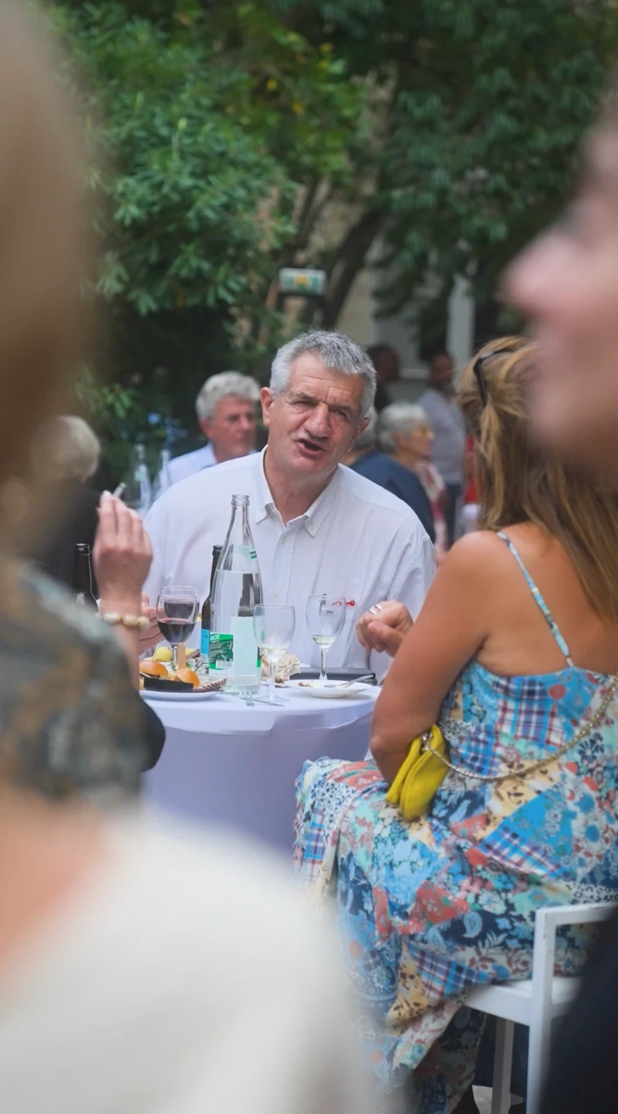 Des convives discutent autour d’une table en extérieur.