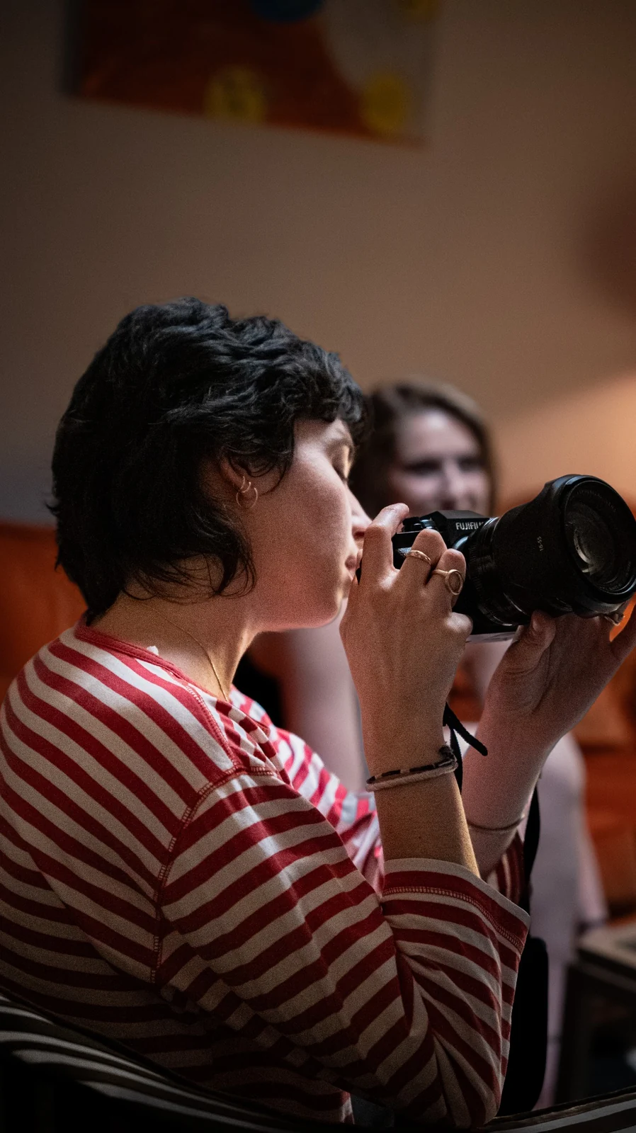 Une personne tenant un appareil photographique dans un intérieur aux tons chauds.