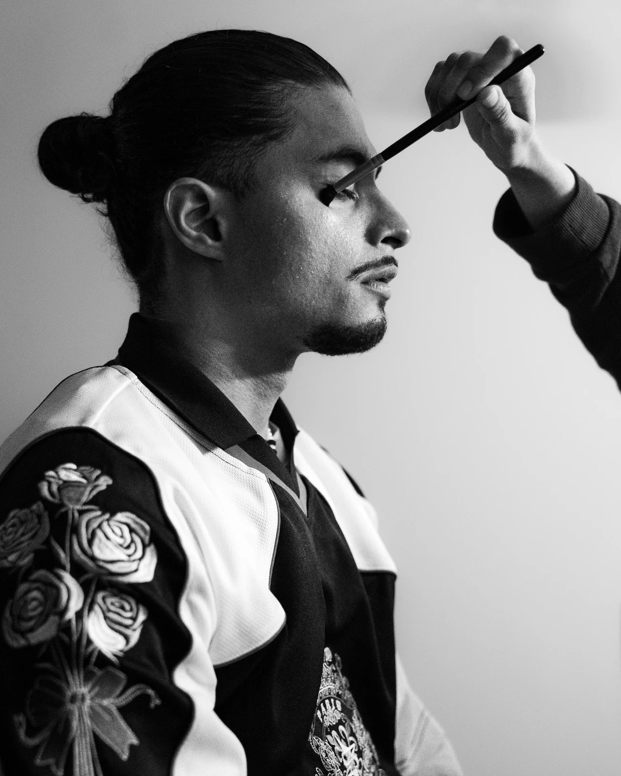 Un geste de maquillage sur un visage de profil, en noir et blanc.