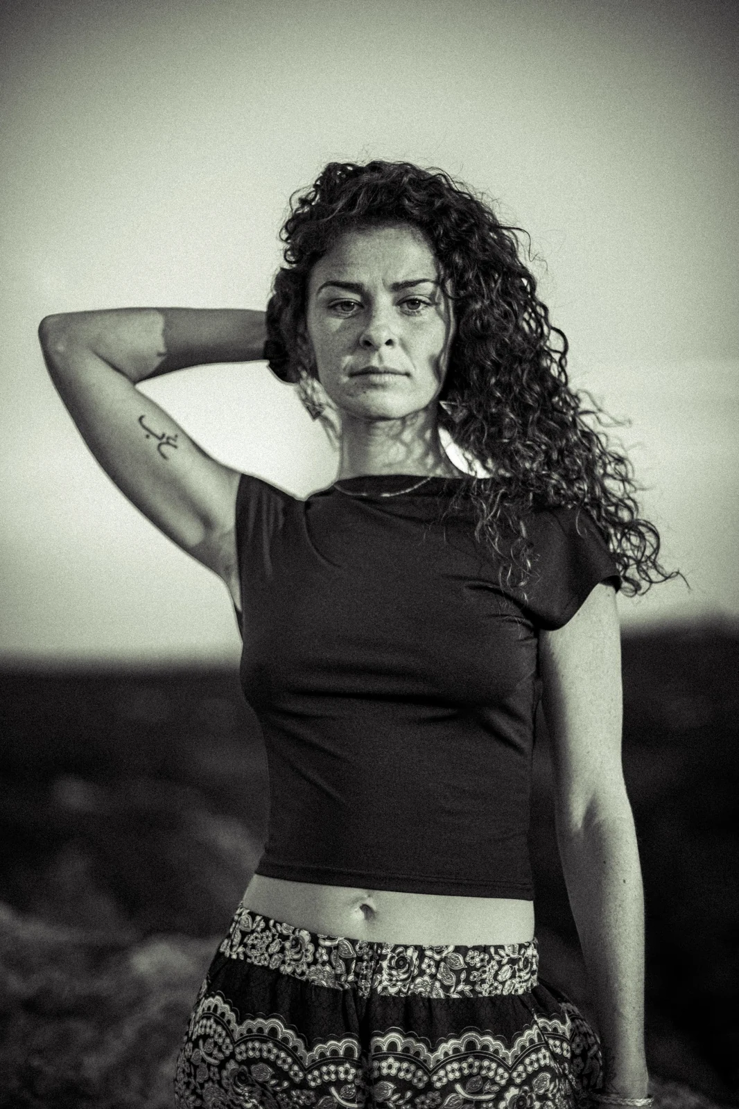 Portrait face caméra, un bras relevé derrière la tête.